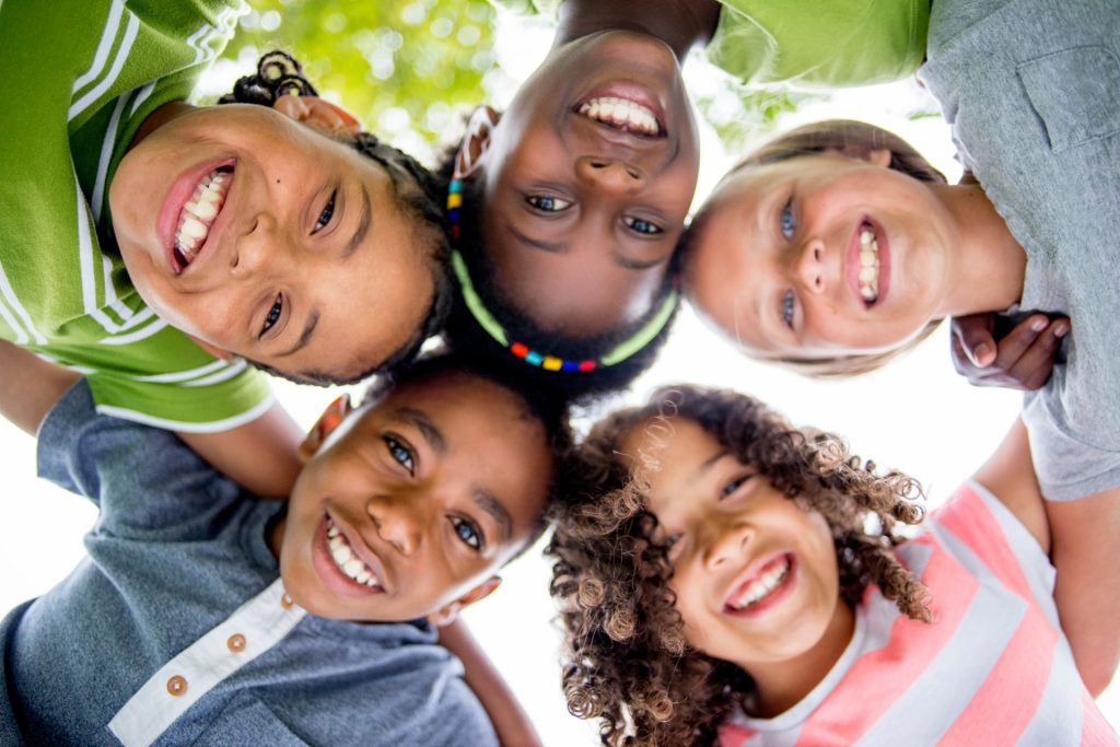 Un groupe de 5 enfants souriants se tenant par les épaules